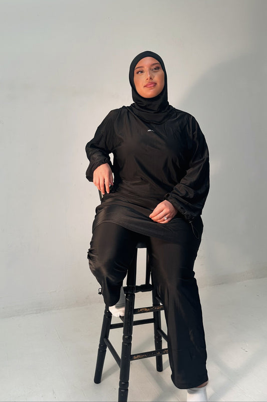 Ensemble modeste noir Ablaa pour sport et lifestyle, composé d’un top long et d’un pantalon ample couvrant, style sobre et fonctionnel
