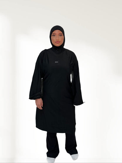 Ensemble modeste noir Ablaa pour sport et lifestyle, composé d’un top long et d’un pantalon ample couvrant, style sobre et fonctionnel

